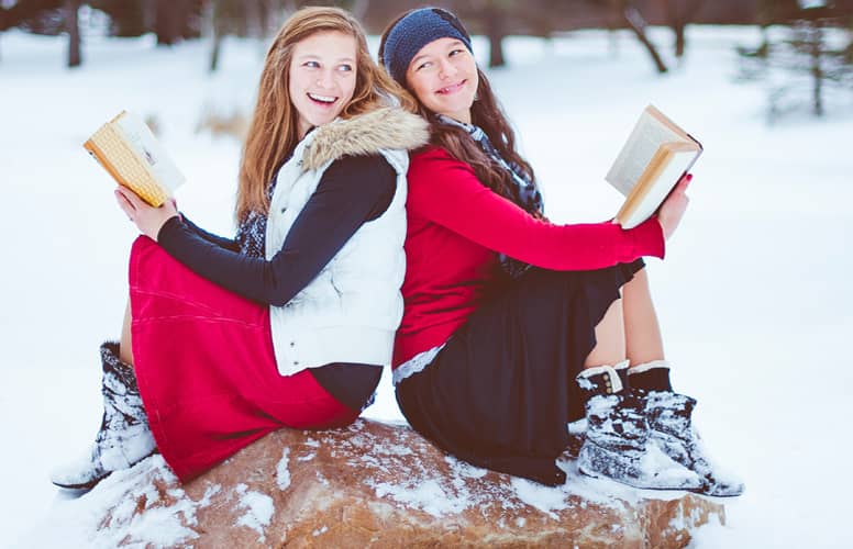 Deux jeunes filles rient dos à dos un livre à la main