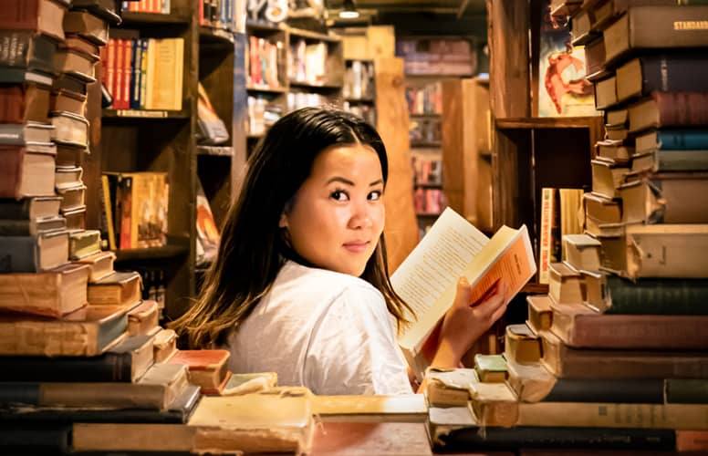 jeune fille lisant un livre dans une bibliothèque
